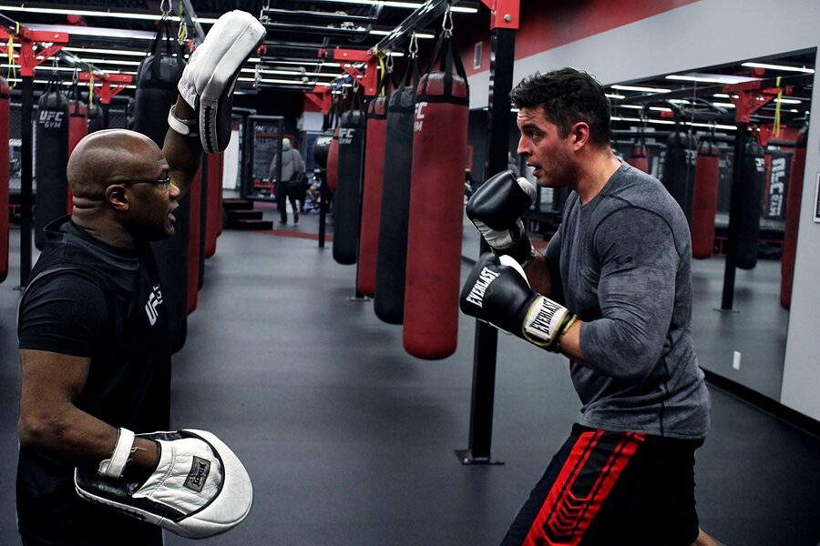 Yves holding focus mitts for a client at UFC Gym